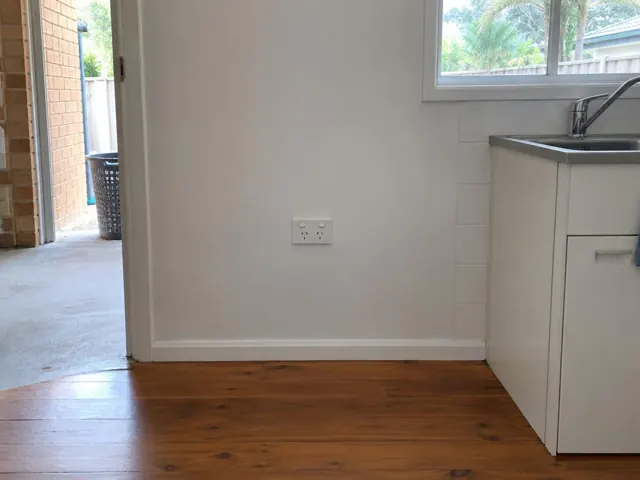 White double power point on a painted kitchen wall beside timber flooring and sink cabinets in Tugun